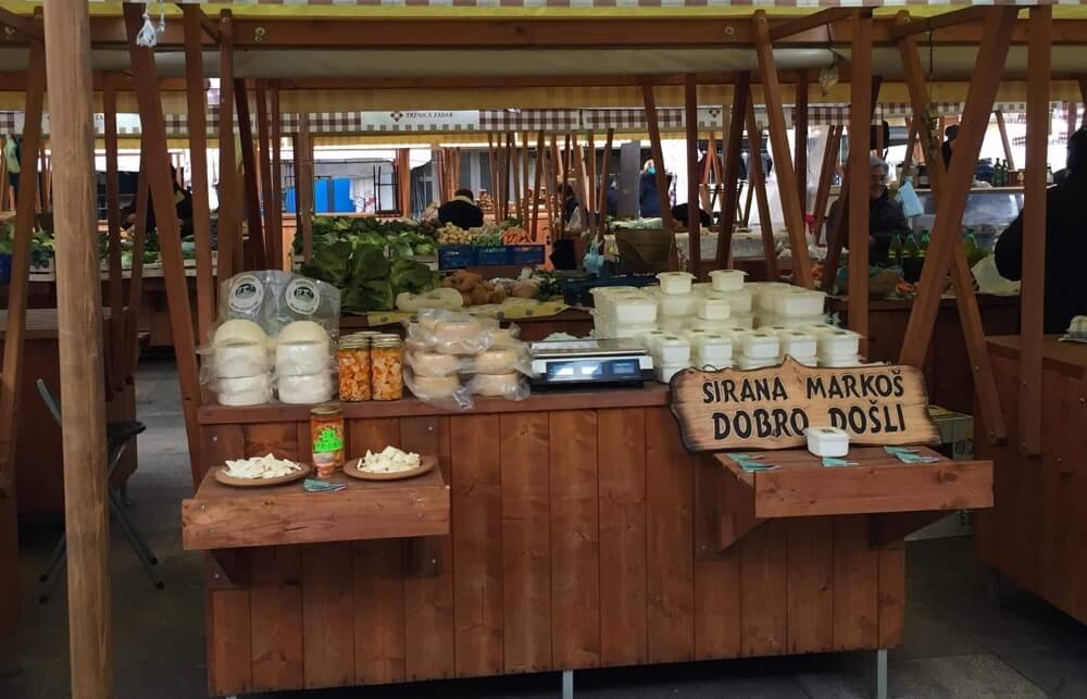 Market stall displaying the OPG Markoš cheeses.