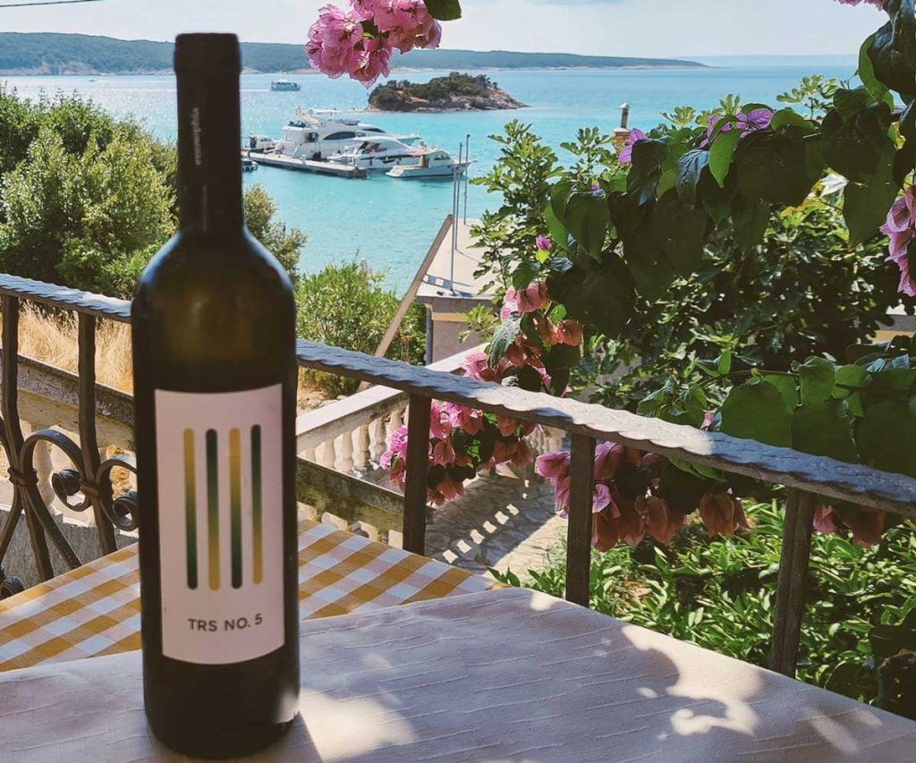 Image of a wine bottle on a table with sea view panorama